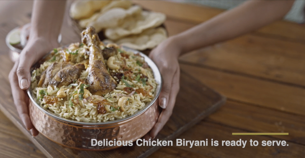A steaming hot chicken biryani garnished with fried onions, cashews, and herbs, prepared with Double Horse Basmati Rice, ready to serve.
