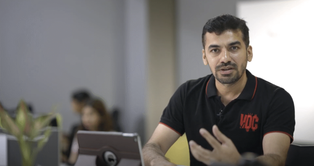A speaker talking to camera in an office setting, from the GITAM film series.