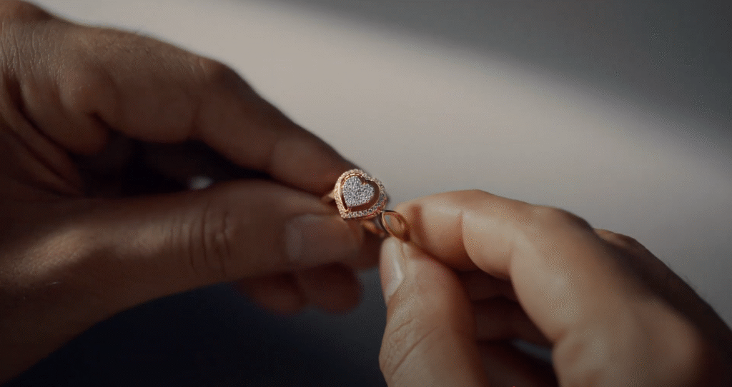 Close-up of hands holding a gold heart-shaped diamond ring for digital film production.