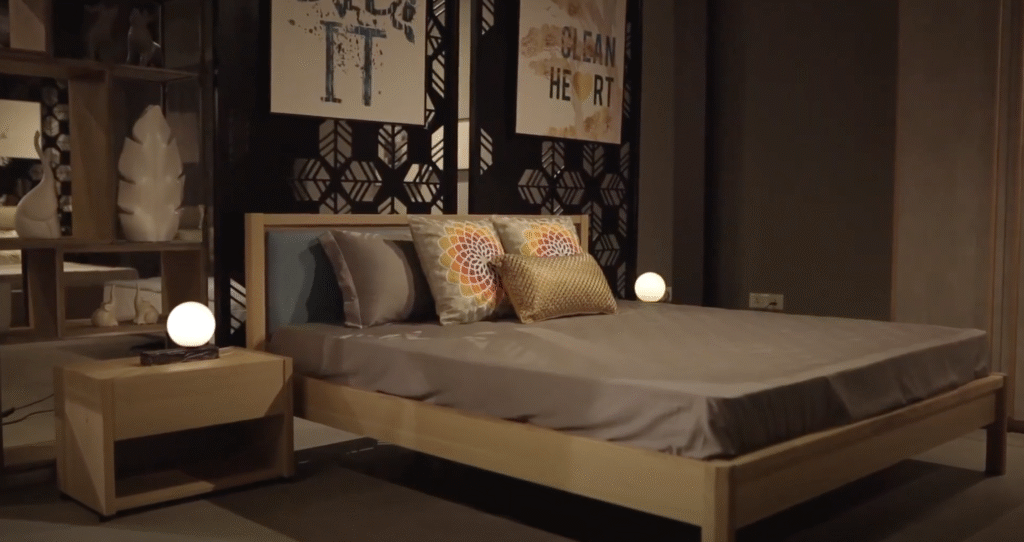 Modern bedroom with a wooden bed, colorful cushions, and warm lighting.