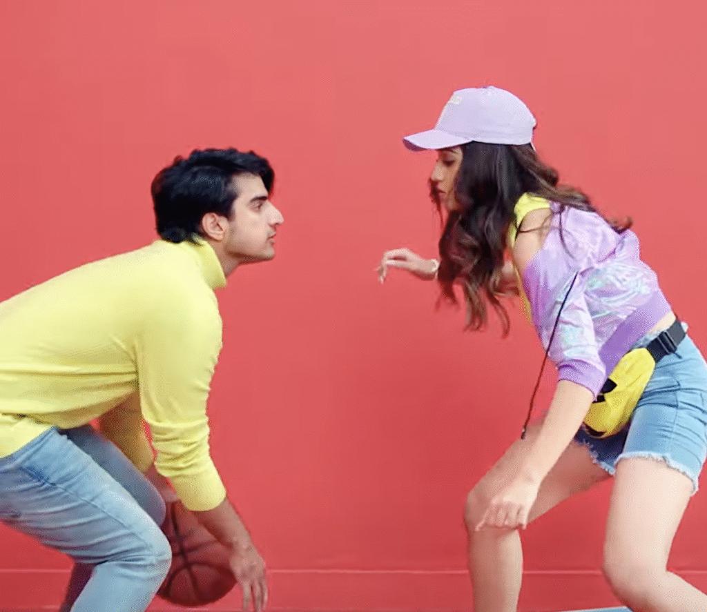 Young man and woman playing basketball against a red background.