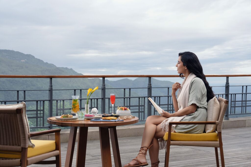A guest enjoying an outdoor meal on a terrace with mountain views at Taj Chia Kutir.