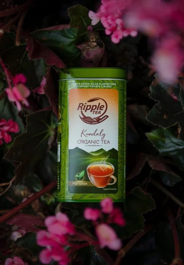 Ripple Tea Kundaly Organic Tea tin placed among vibrant pink flowers and dark green leaves.