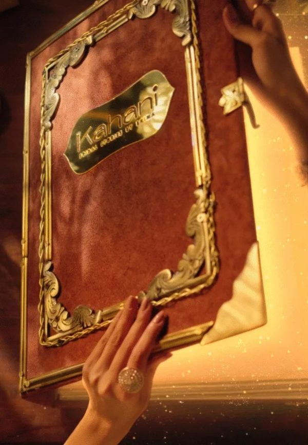 Hands holding an ornate, gold-trimmed menu book with the label “Kahani” against a warm, glowing background.